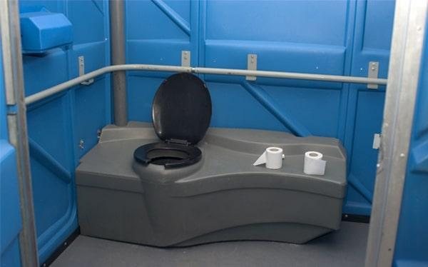 Interior of ADA-accessible portable toilet showing grab bars and open turning space